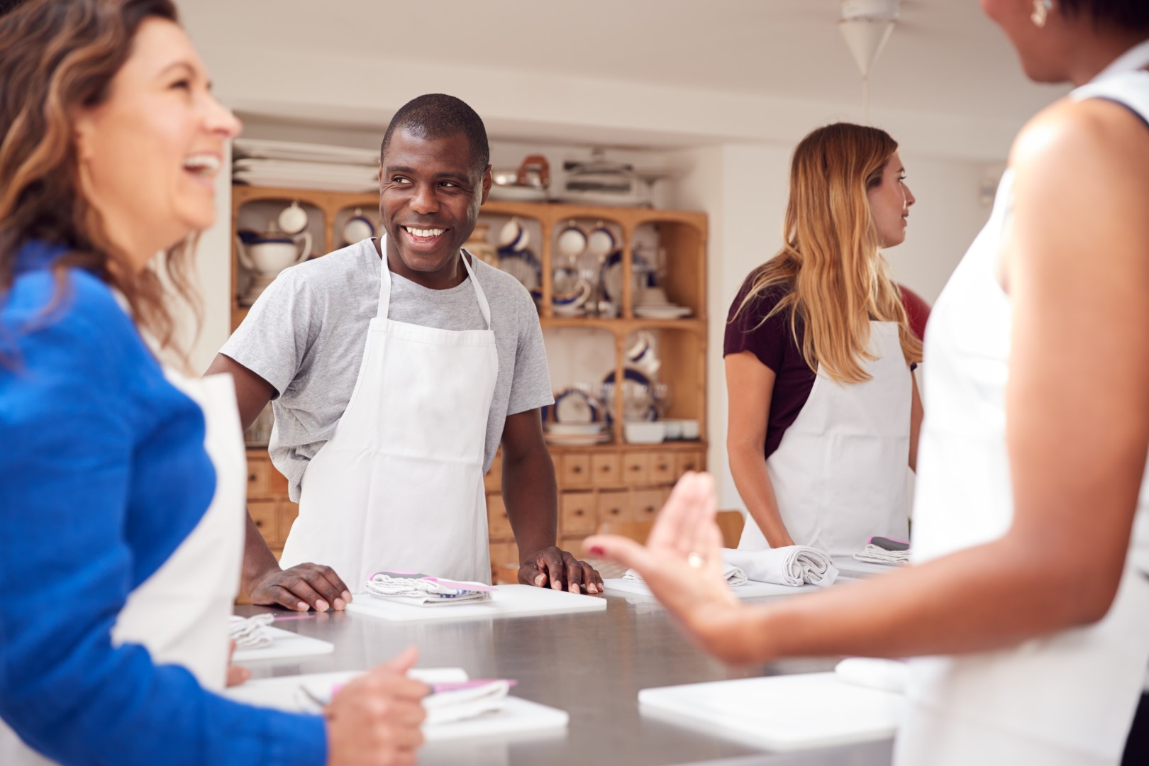 Male And Female Students Standing With Chopping Boards At Start Of Cookery Class In Kitchen